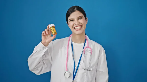 年轻美丽的惊慌失措的女医生在孤零零的蓝色背景下吃药 — 图库照片