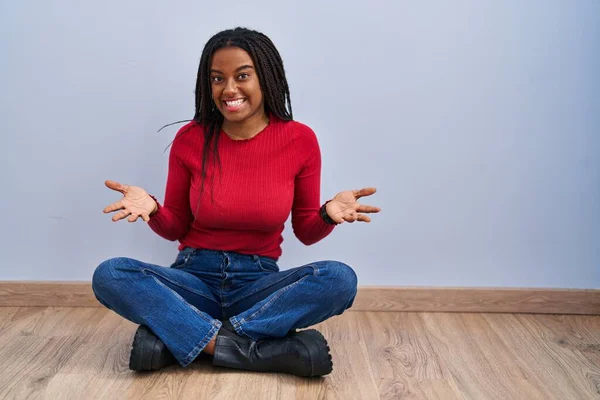Młody Afroamerykanin Warkoczami Siedzący Podłodze Domu Uśmiechnięty Pogodny Otwartymi Ramionami — Zdjęcie stockowe