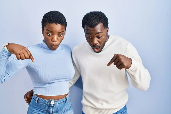 Młoda Afrykańska Para Stojąca Nad Niebieskim Tłem Palcami Pokazującymi Reklamę — Zdjęcie stockowe