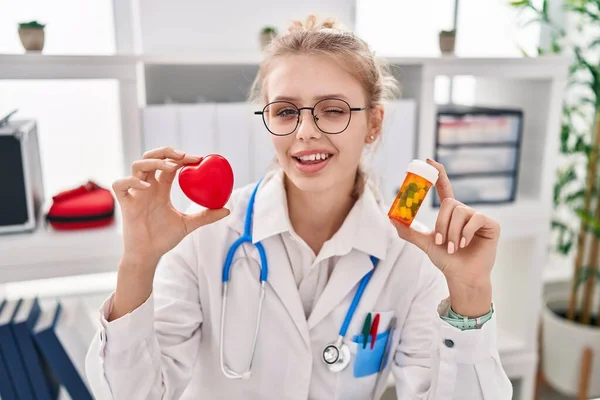 Jovem Médico Caucasiano Mulher Segurando Pílulas Coração Piscando Olhando Para — Fotografia de Stock