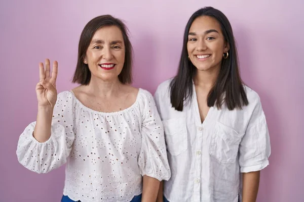 西班牙裔母亲和女儿在一起 带着自信和快乐的笑容 用第三根手指指指着对方 — 图库照片