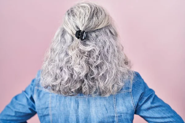 中年妇女 灰白的头发站在粉红的背景上 背向后看去 两臂交叉在身上 — 图库照片