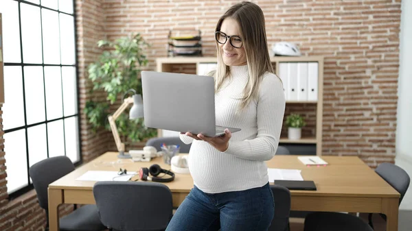 年轻的怀孕女工在办公室使用笔记本电脑 自信地微笑着 — 图库照片