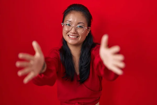 Azjatka Młoda Kobieta Stojąca Nad Czerwonym Tłem Patrząca Kamerę Uśmiechnięta — Zdjęcie stockowe
