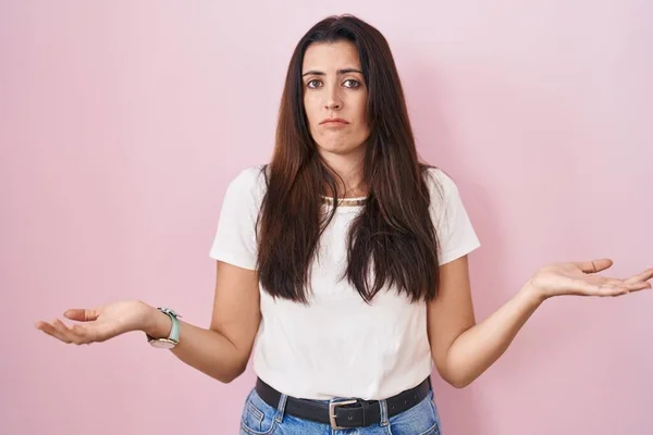 Young Brunette Woman Standing Pink Background Clueless Confused Open Arms — Stock Photo, Image