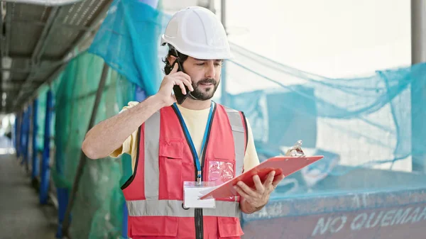 Joven Constructor Hispano Hablando Por Teléfono Inteligente Leyendo Documento Calle —  Fotos de Stock