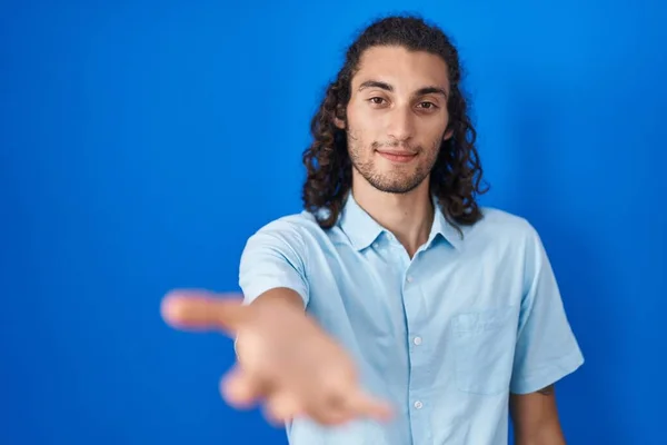 Jonge Spaanse Man Staat Blauwe Achtergrond Glimlachend Vrolijk Aanbieden Palm — Stockfoto