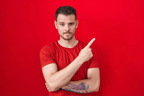 Jonge Spaanse Man Staat Rode Achtergrond Wijzend Met Hand Vinger — Stockfoto