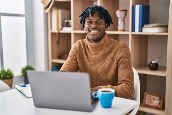 年轻的非洲男人 带着可怕的头发 用电脑笔记本电脑工作 脸上带着快乐而沉着的笑容 幸运的人 — 图库照片
