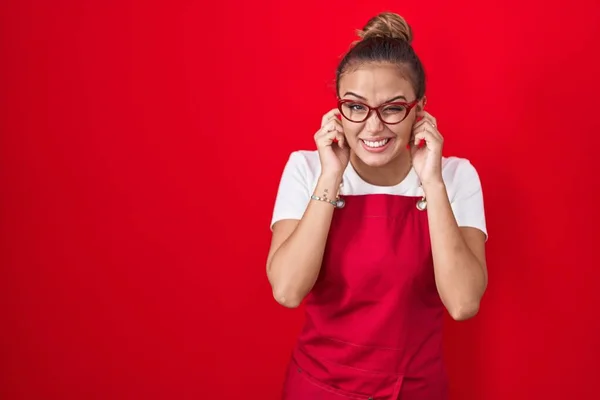 Tânără Hispanică Poartă Șorț Chelneriță Fundal Roșu Acoperind Urechile Degetele — Fotografie, imagine de stoc
