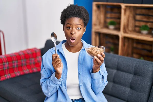 stock image African american woman eating healthy whole grain cereals afraid and shocked with surprise and amazed expression, fear and excited face. 