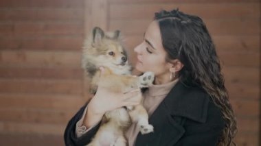 Köpeğiyle gülümseyen genç İspanyol kadın izole edilmiş ahşap arka planda duruyor.