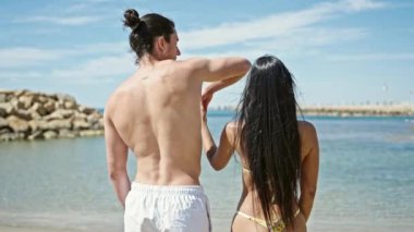 Erkek ve kadın turist çift sahilde birbirlerine sarılıyorlar.