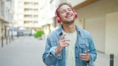 Sokak ortasında müzik dinleyen ve dans eden beyaz bir genç.