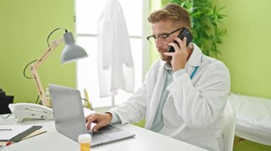 Kafkasyalı genç doktor, klinikteki akıllı telefondan dizüstü bilgisayar kullanıyor.
