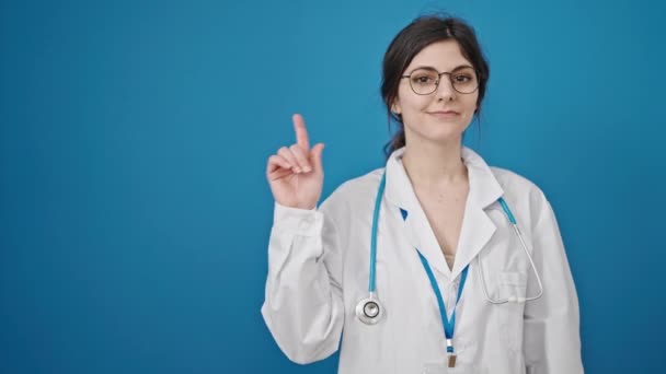 Dokter Muda Hispanik Tersenyum Menunjuk Sisi Atas Latar Belakang Biru — Stok Video