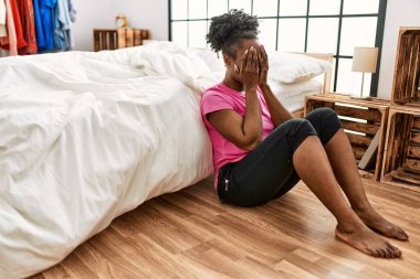 African american woman stressed sitting on floor at bedroom