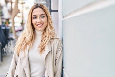 Young blonde woman smiling confident looking to the side at street