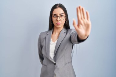 Gözlüklü İspanyol iş kadını avucuyla şarkı söylemeyi kesiyor. Yüzünde olumsuz ve ciddi bir jest olan uyarı ifadesi. 