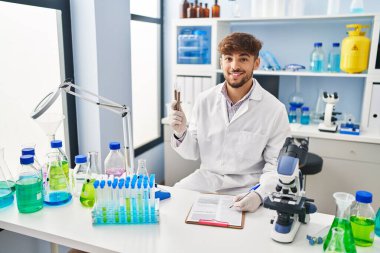 Genç Arap bilim adamı, laboratuardaki mercimek test tüplerini analiz eden bir belge hazırlıyor.