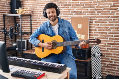 Genç Arap müzisyen müzik stüdyosunda klasik gitar çalıyor.