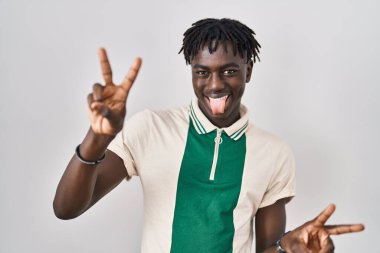 Münzevi arka planda dikilen Afrikalı adam her iki elinde parmaklarını göstererek gülümseyerek zafer işareti yapıyor. İki numara.. 