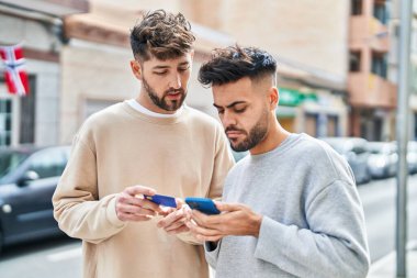 Young couple using smartphone and credit card standing together at street