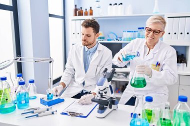 Mother and son scientist partners measuring liquid at laboratory