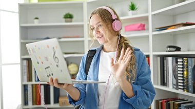 Kütüphanede videolu görüşme yapan genç sarışın kız öğrenci.