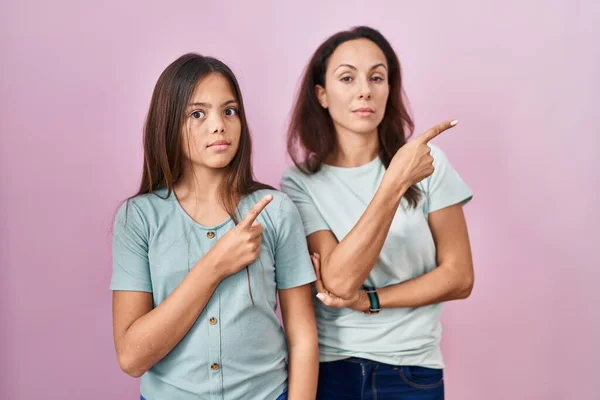 Pembe Arka Planda Duran Genç Anne Kız Parmaklarıyla Reklamı Gösteriyor — Stok fotoğraf