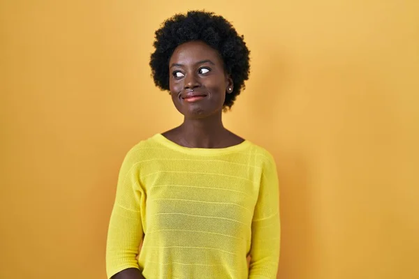 Afrikaanse Jonge Vrouw Staan Gele Studio Glimlachen Kijken Naar Zijkant — Stockfoto