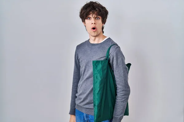 再利用可能な袋を身に着けている若い男は怖がって 驚きのために口を開けて驚いて 不信の顔 — ストック写真