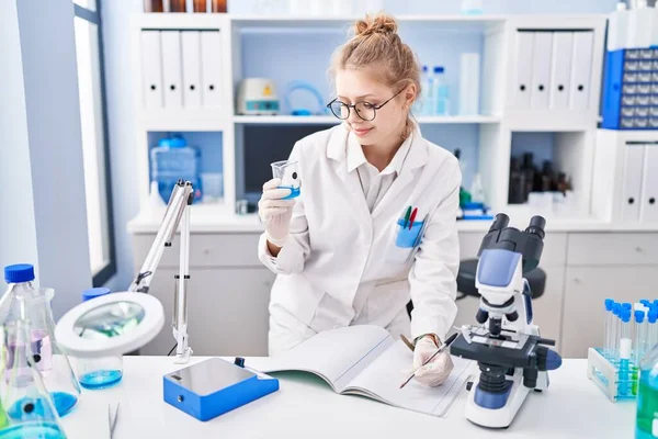 Young Blonde Woman Scientist Writing Notebook Holding Test Tube Laboratory —  Fotos de Stock