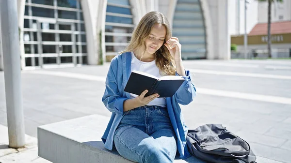 Νεαρή Ξανθιά Φοιτήτρια Διαβάζει Βιβλίο Καθισμένη Στον Πάγκο Στο Πανεπιστήμιο — Φωτογραφία Αρχείου