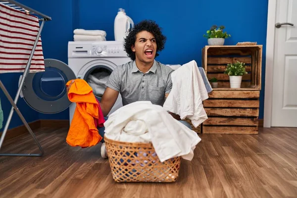 头发卷曲的西班牙裔男子在洗衣房洗衣服 愤怒而疯狂地尖叫 愤怒而沮丧 愤怒和好斗的概念 — 图库照片