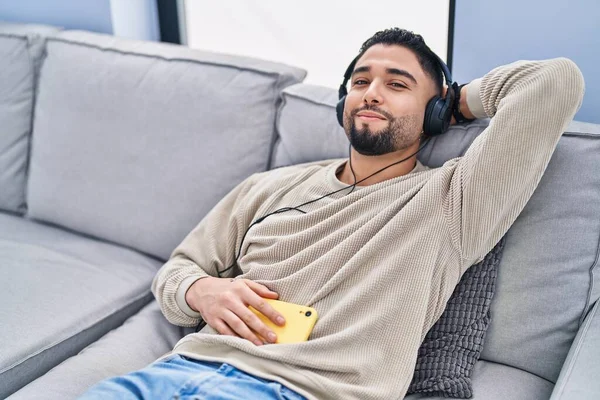 Mladý Arabský Muž Poslouchá Hudbu Spící Pohovce Doma — Stock fotografie