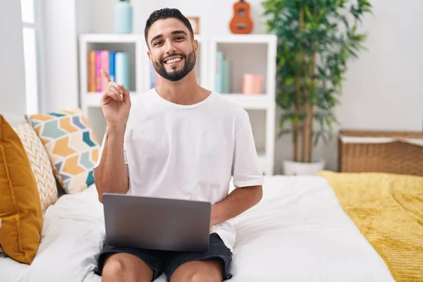 Jovem Hispânico Usando Laptop Computador Sentado Cama Sorrindo Feliz Apontando — Fotografia de Stock