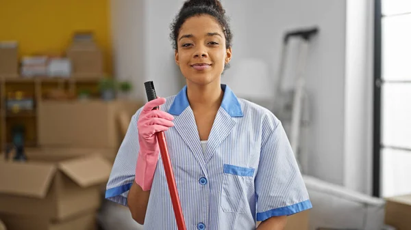 African american woman clean professional holding mop smiling at new home
