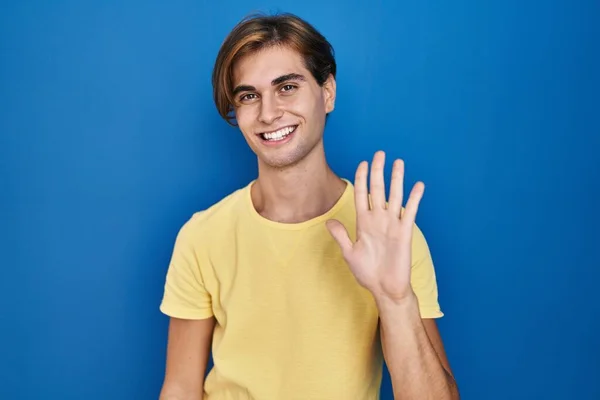 年轻人站在蓝色的背景上 用五号手指指指指点点 面带微笑 自信而快乐 — 图库照片