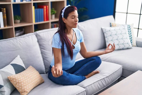 年轻美丽的惊慌失措的女人坐在家里的沙发上做瑜伽运动 — 图库照片