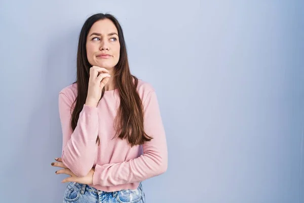 Young Brunette Woman Standing Blue Background Hand Chin Thinking Question — стоковое фото