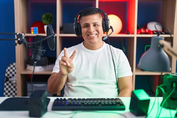 Young Hispanic Man Playing Video Games Showing Pointing Fingers Number — Stok fotoğraf