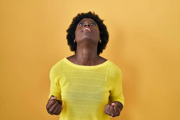 黄色のスタジオの上に立っているアフリカの若い女性は怒りと怒りで叫んで フラストレーションと怒りを叫んで怒っています 怒りと攻撃的な考え方 — ストック写真