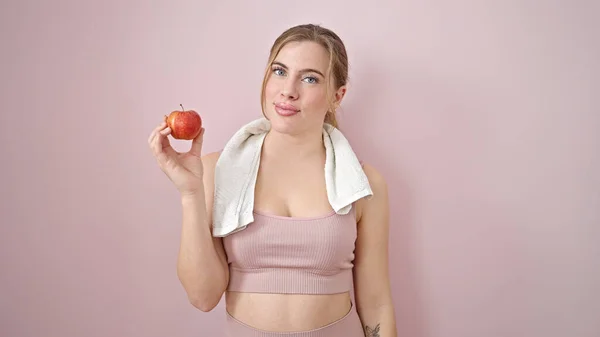 Ung Blond Kvinna Bär Sportkläder Håller Äpple Över Isolerad Rosa — Stockfoto