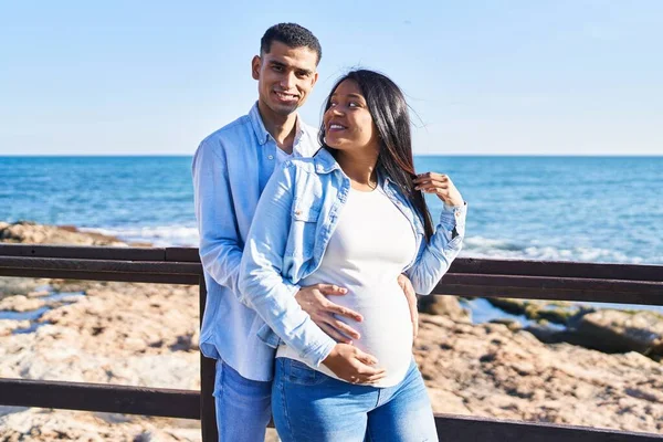 Young Latin Couple Expecting Baby Hugging Each Other Standing Seaside — Stock fotografie