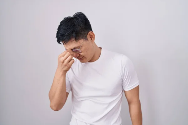 白い背景に立っている若いアジア人男性疲れ鼻と目の疲労感や頭痛をこすり ストレスとフラストレーションの概念 — ストック写真