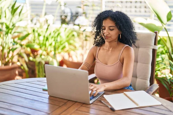 stock image Young hispanic woman using laptop sitting on table at home terrace