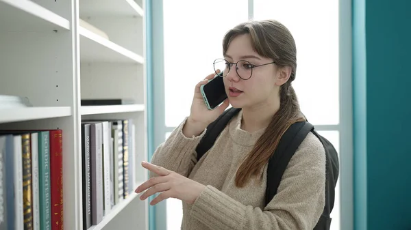 若いですブロンド女性学生話して上のスマートフォンで図書館大学 — ストック写真