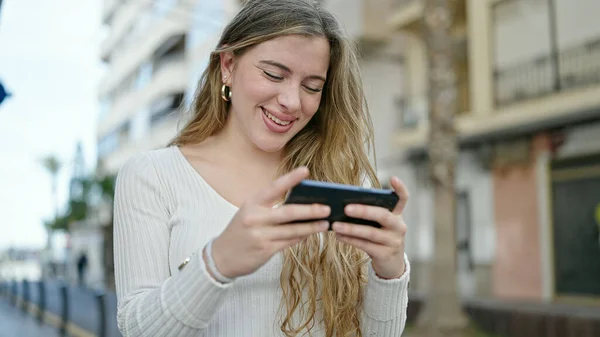 Νεαρή Ξανθιά Γυναίκα Χαμογελά Αυτοπεποίθηση Βλέποντας Βίντεο Onsmartphone Στο Δρόμο — Φωτογραφία Αρχείου