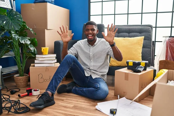 Hombre Afroamericano Sentado Suelo Nueva Casa Mostrando Señalando Hacia Arriba —  Fotos de Stock